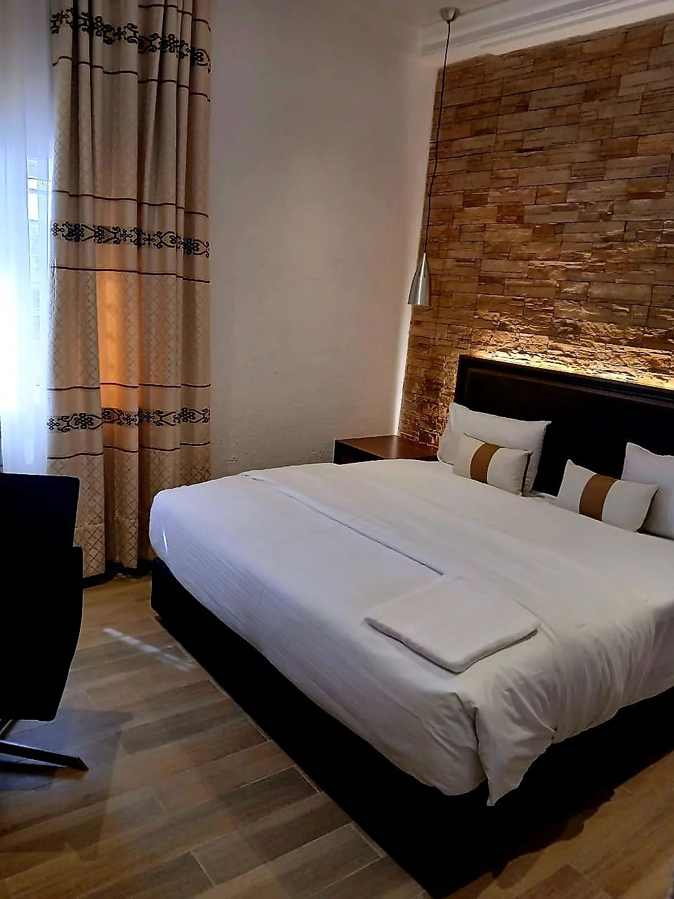 Deluxe Room category with a made bed and bedside lighting