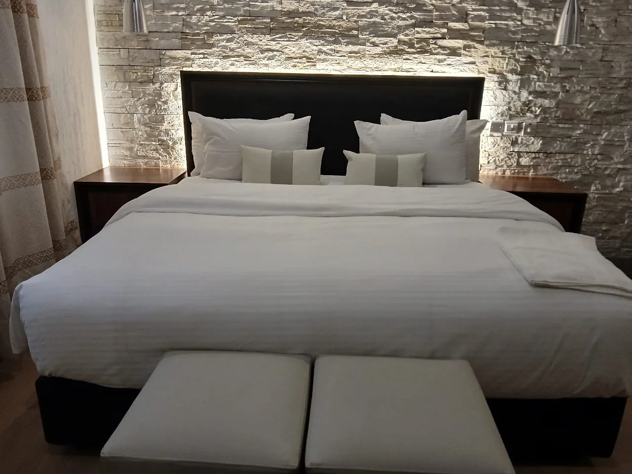Deluxe King Room category with a made king bed and dark feature wall